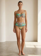 Driftly green ethnic print high-waisted bikini set with ruched sides and secure straps, in a minimalist studio setting with soft window light.