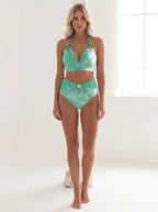 Driftly green printed bikini top with adjustable straps, matching high-waisted bottoms, in a minimalist studio setting with soft window light.