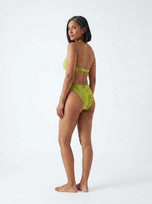 Woman wearing an olive green halter bikini set with bamboo swirl print, studio photography, back view