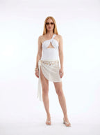 Woman wearing a white cut-out bikini set with tie-front sarong skirt, studio photography, front view