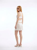 Woman wearing a white cut-out bikini set with tie-front sarong skirt, studio photography, back view
