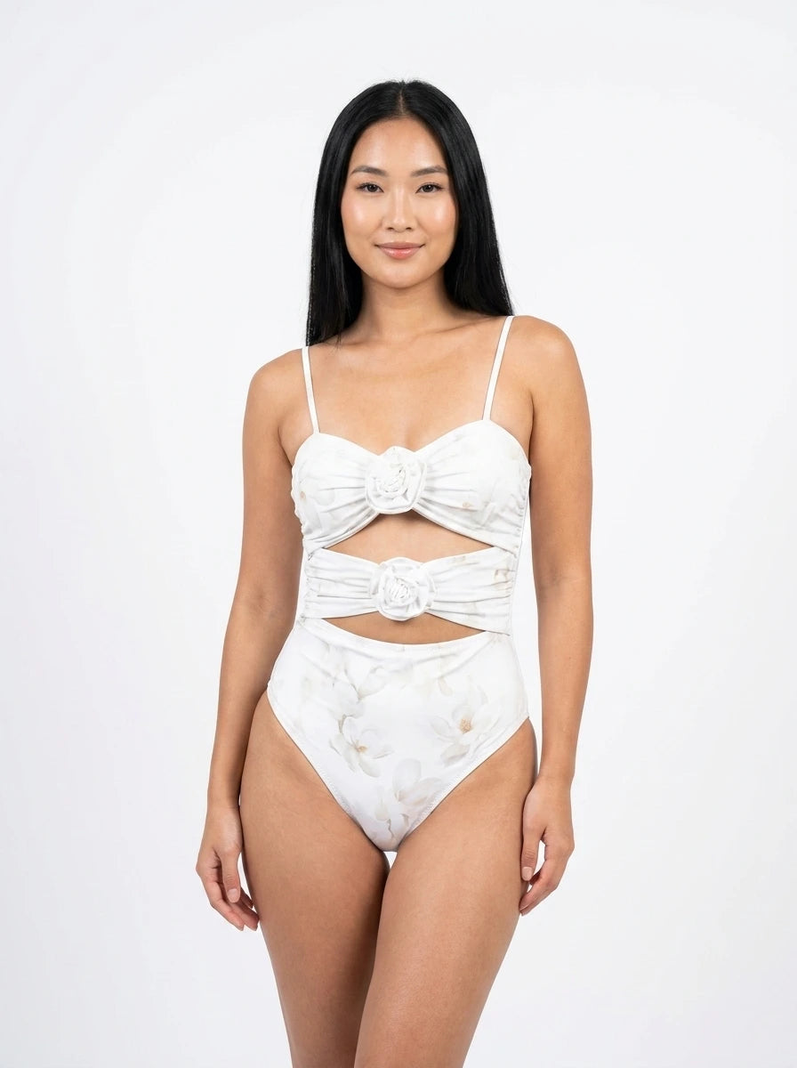 Woman wearing a white floral print swimsuit set with bow detail, studio photography, front view