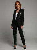 Woman wearing a black double-breasted tailored blazer and trouser set in a studio setting