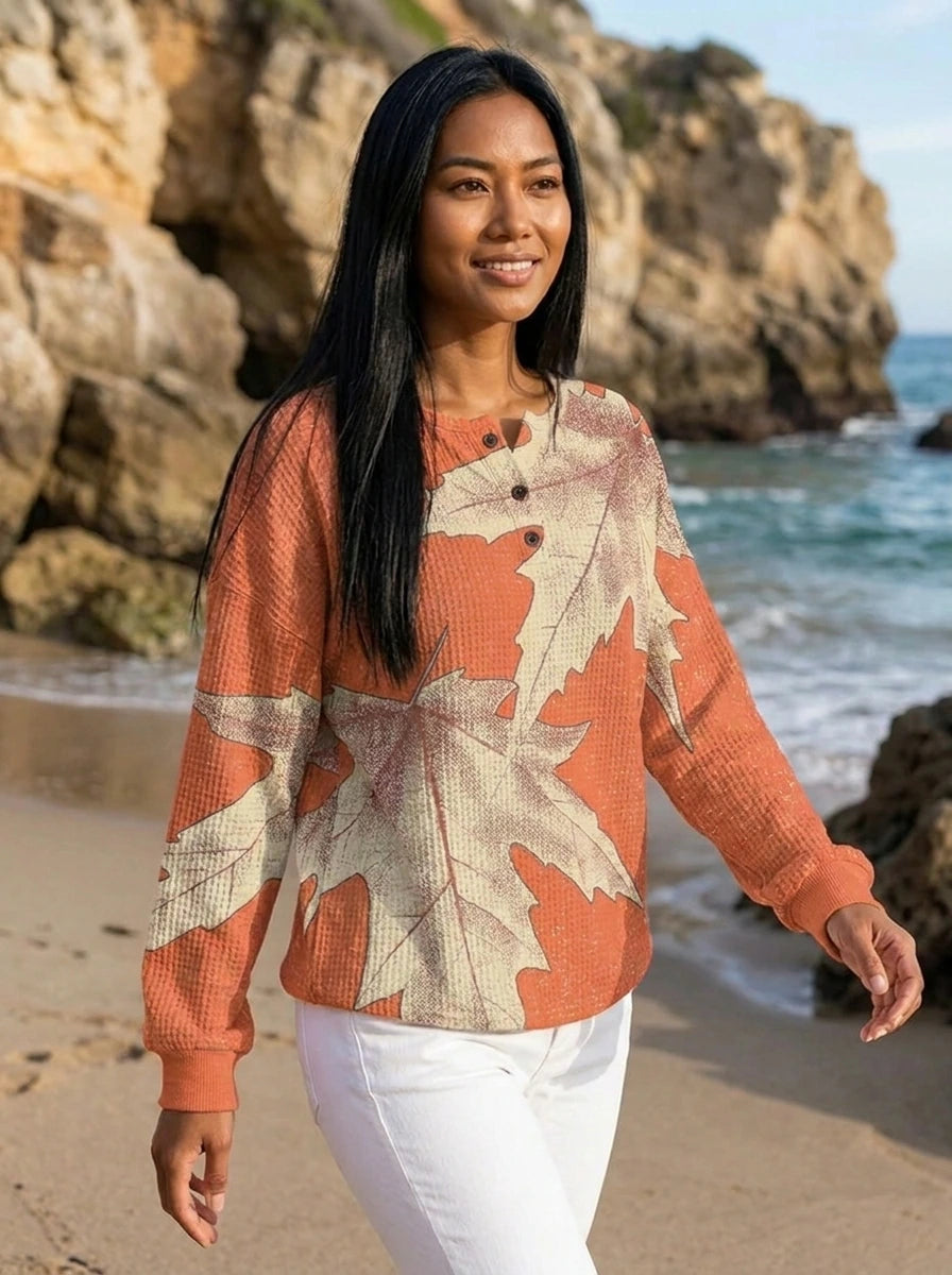 Woman walking on the beach wearing a peach leaf print long sleeve blouse