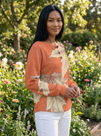 Woman wearing a peach leaf print long sleeve blouse in a garden setting