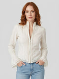 Woman wearing a white bohemian lace blouse with flared sleeves in a studio setting