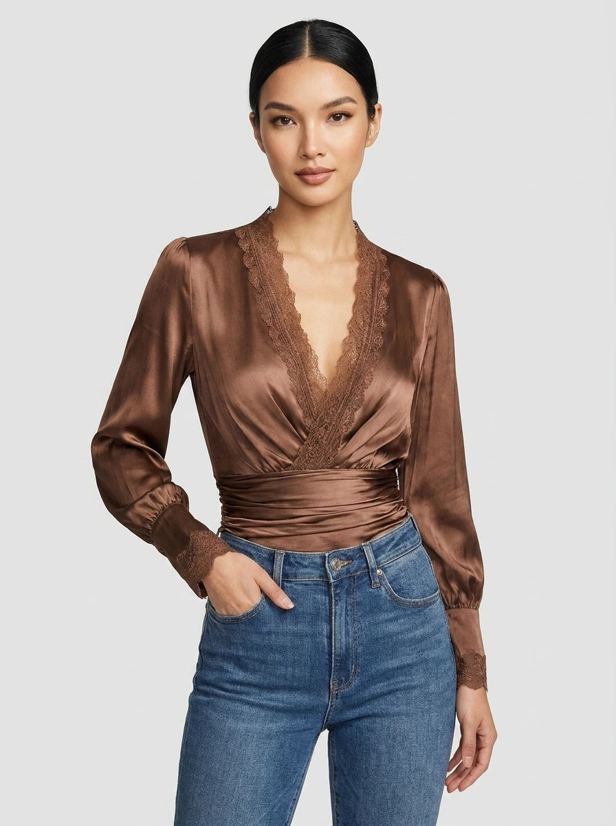 Woman wearing a bronze satin wrap blouse with lace trim in a studio setting