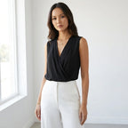 Driftly women's black sleeveless soft-touch blouse, styled with white wide-leg trousers in a minimalist studio setting.