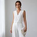Driftly women's white sleeveless soft-touch blouse, styled with white wide-leg trousers in a minimalist studio setting.