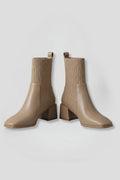 Woman wearing khaki block heel ankle boots - studio photo
