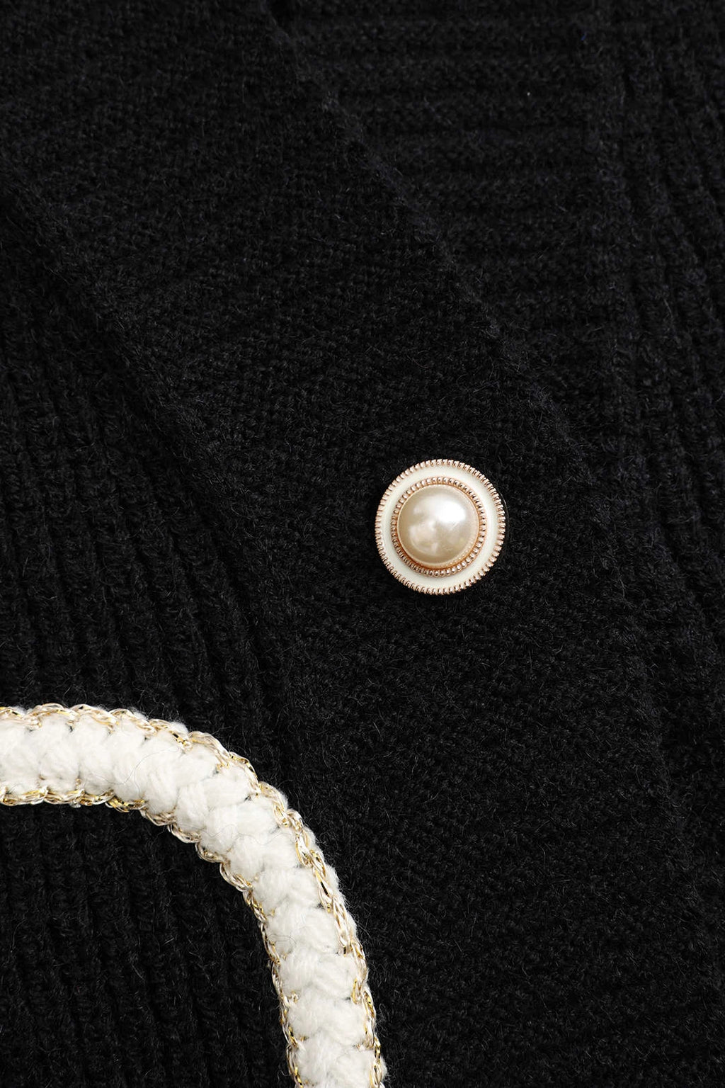 Close-up of pearl-style button detail on black cardigan