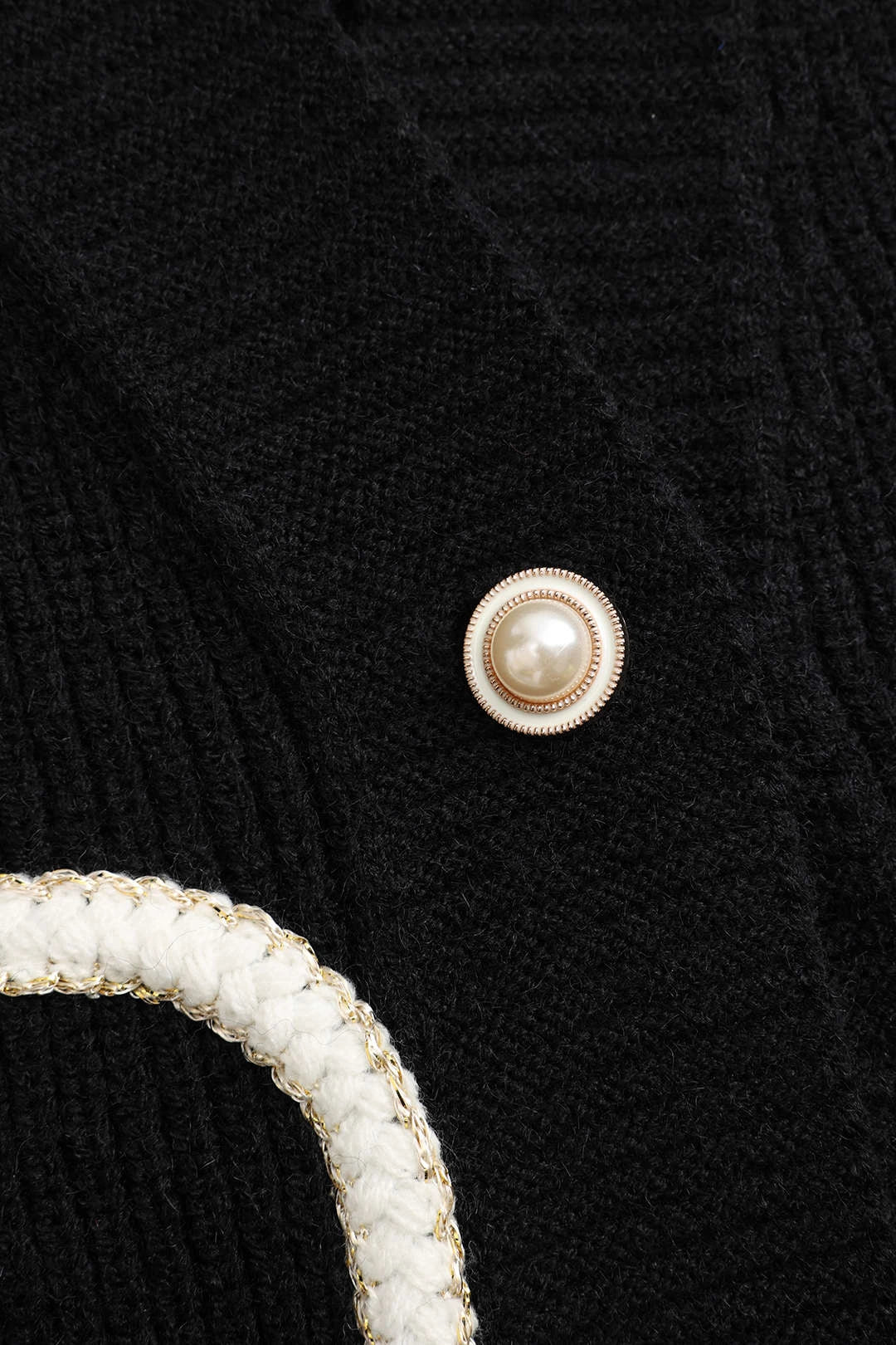 Close-up of pearl-style button detail on black cardigan