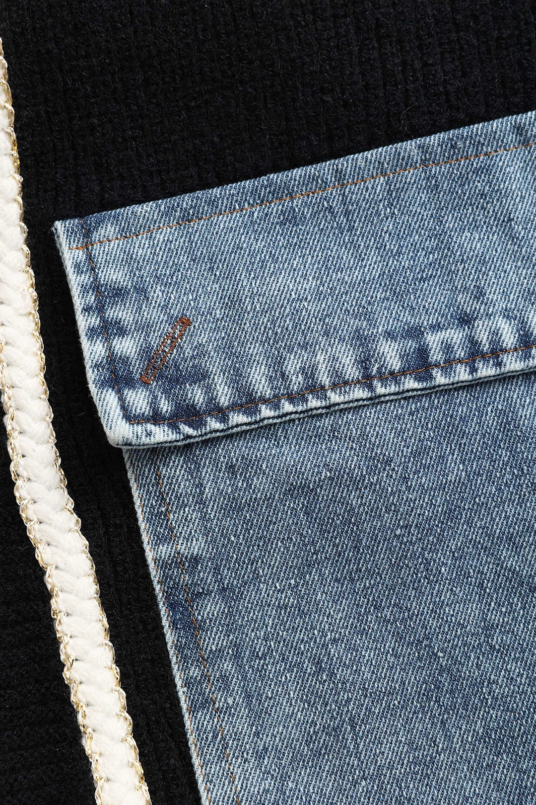 Close-up of denim patch pocket detail on black cardigan