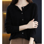 Woman wearing a black wool cashmere button-up cardigan in a studio setting