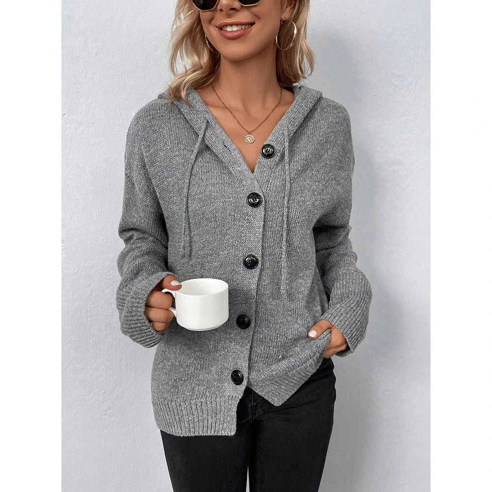 Woman wearing grey hooded button-up cable knit cardigan holding a mug