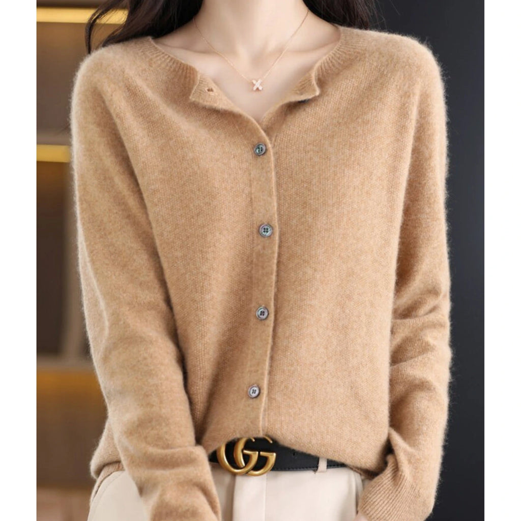 Woman wearing a light brown wool cashmere button-up cardigan in a studio setting