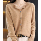 Woman wearing a light brown wool cashmere button-up cardigan in a studio setting