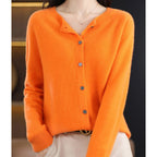 Woman wearing an orange wool cashmere button-up cardigan in a studio setting