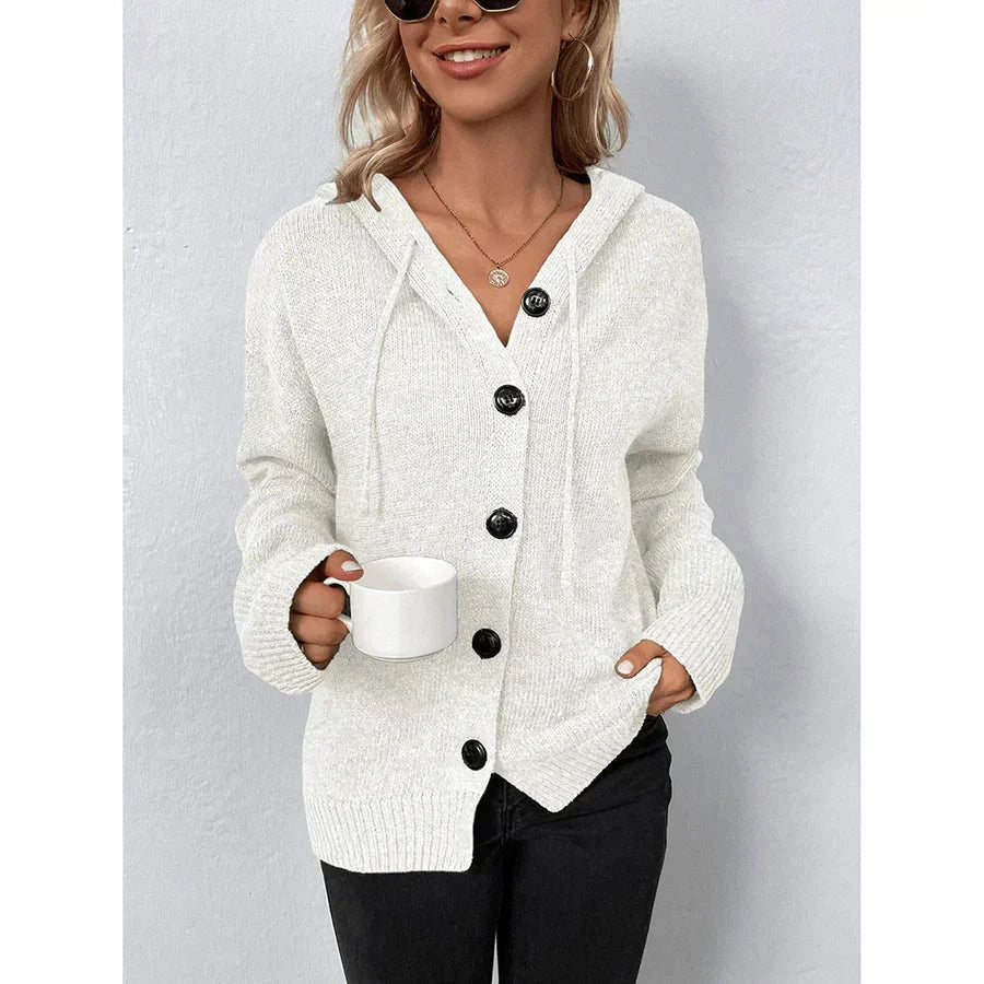 Woman wearing white hooded button-up cable knit cardigan holding a mug