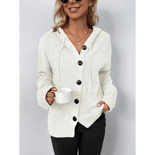 Woman wearing white hooded button-up cable knit cardigan holding a mug