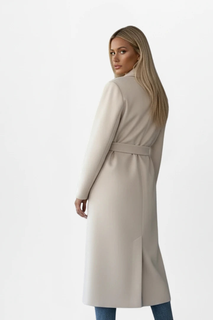 Woman wearing a cream double-breasted belted long coat - studio photo