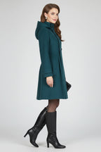 Woman wearing a green hooded double button-front coat - studio photo