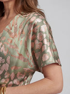 Woman wearing a green abstract print v-neck twist-waist midi dress - studio photo