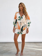 Woman wearing a white tropical floral kimono cover-up and shorts set in a bright studio setting