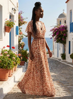 Woman wearing a rust and terracotta floral print boho maxi dress on a sunny Mediterranean street