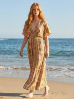Woman wearing an olive green and pink floral print boho kaftan maxi dress on a sunny beach