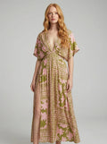Woman wearing an olive green and pink floral print boho kaftan maxi dress in a studio setting