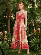 Woman wearing a red paisley print halter maxi dress in a tropical garden
