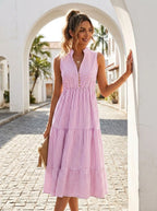 Woman wearing a pink and white pinstriped tiered midi dress on a sunny street
