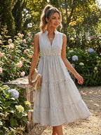 Woman wearing a white and grey pinstriped tiered midi dress in a sunlit garden