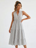 Woman wearing a white and grey pinstriped tiered midi dress in a bright studio setting