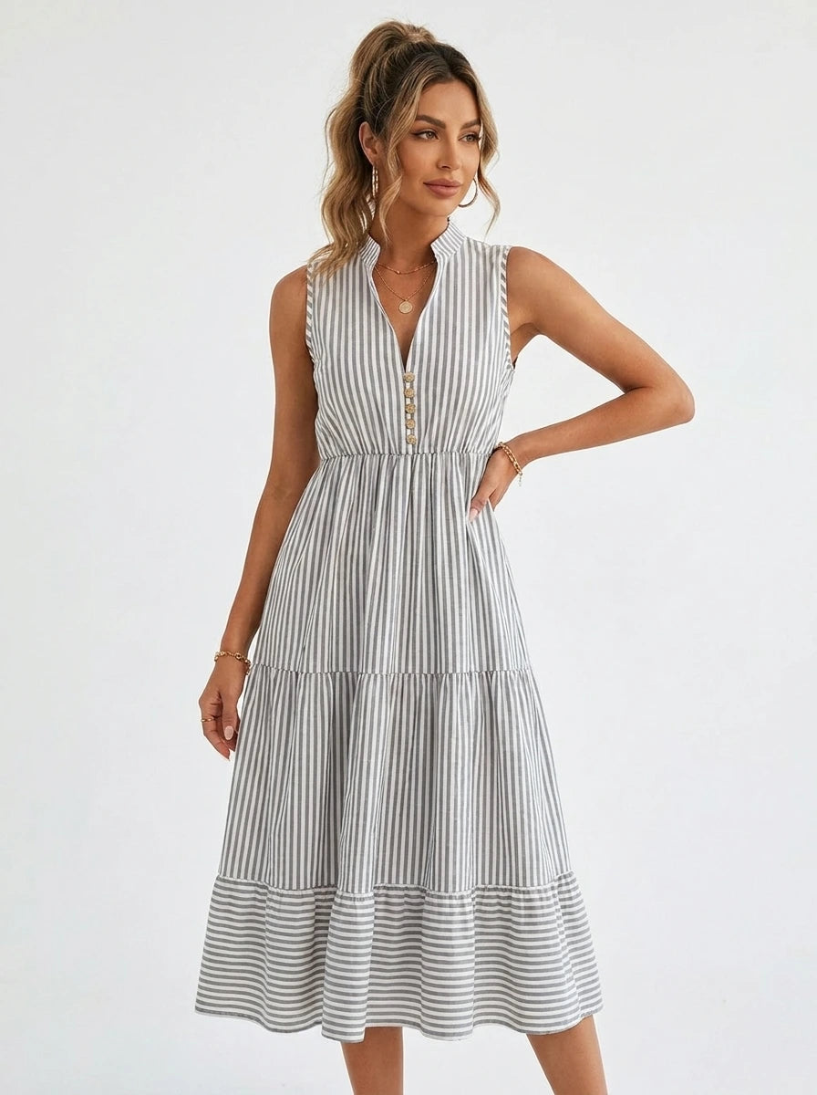 Woman wearing a white and grey pinstriped tiered midi dress in a bright studio setting