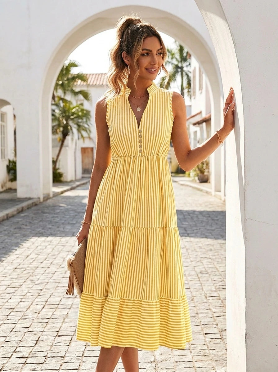 Woman wearing a yellow and white pinstriped tiered midi dress on a sunny street