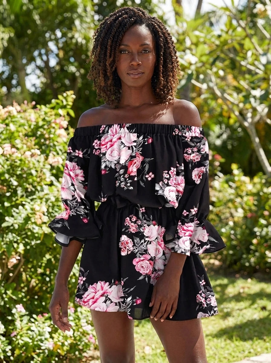 Woman wearing a black floral off-shoulder mini dress in a sunlit garden