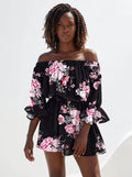Woman wearing a black floral off-shoulder mini dress in a bright studio setting