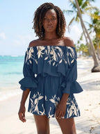 Woman wearing a navy blue floral off-shoulder mini dress on a tropical beach