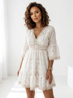 Woman wearing a white crochet lace boho dress in a bright studio setting