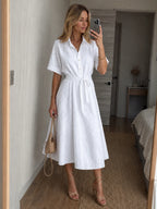 Woman wearing a white button-front waist tie midi dress - studio photo