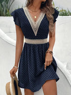 Woman wearing a dark blue chiffon short sleeve v-neck dress - lifestyle photo