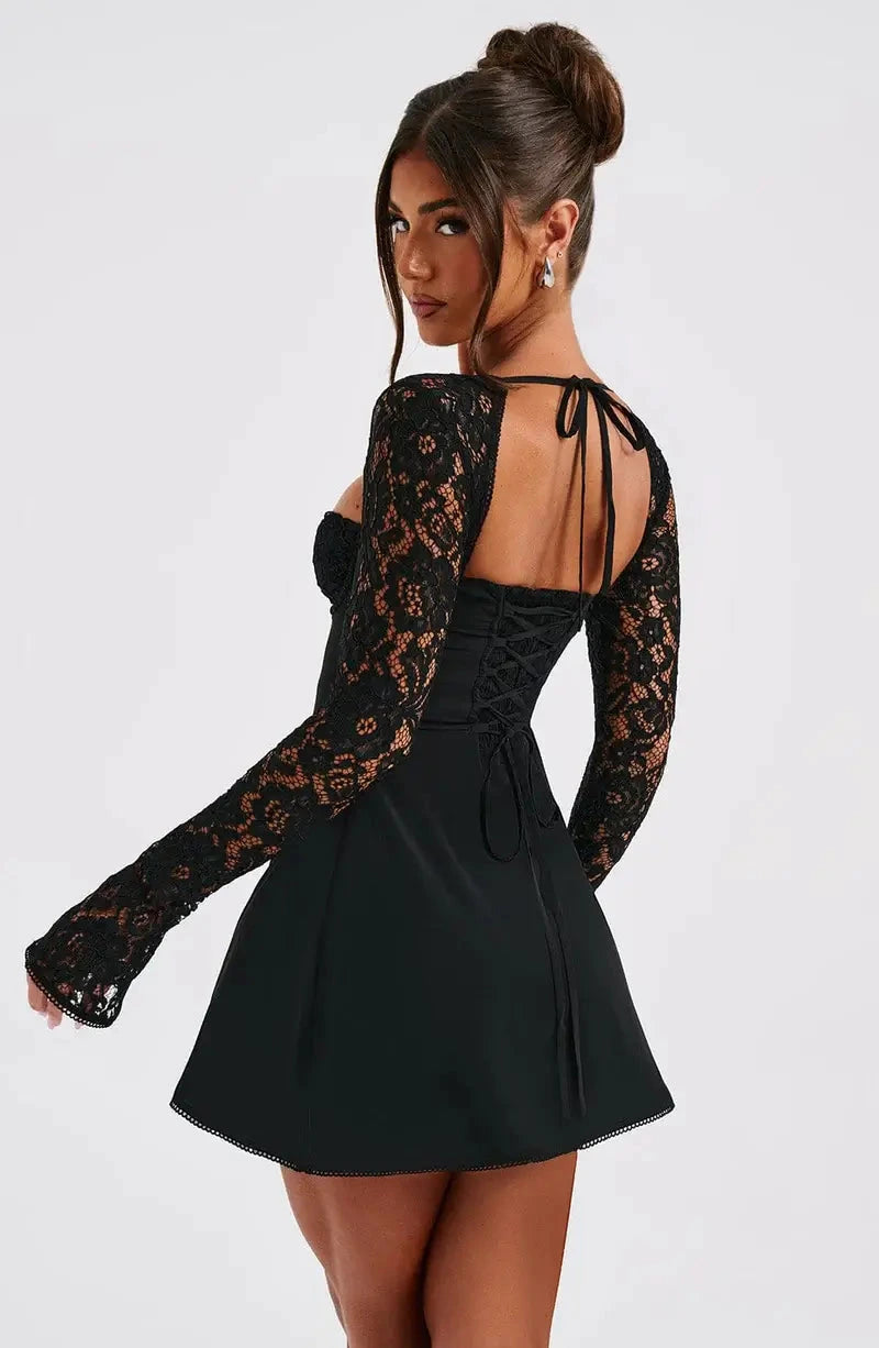 Woman wearing a black corset back long sleeve mini dress - studio photo