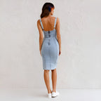 Woman wearing a blue denim sleeveless midi dress - studio photo