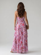Woman wearing a pink floral halter neck ruched maxi dress - studio photo