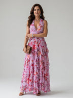 Woman wearing a pink floral halter neck ruched maxi dress - studio photo