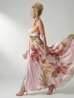 Woman wearing a pink floral halter tie-neck maxi dress - studio photo