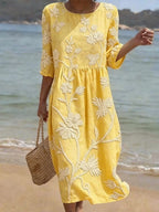 Woman wearing a yellow floral round neck midi dress - lifestyle photo