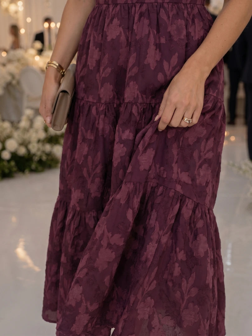 Woman wearing a burgundy floral textured short sleeve midi dress - studio photo